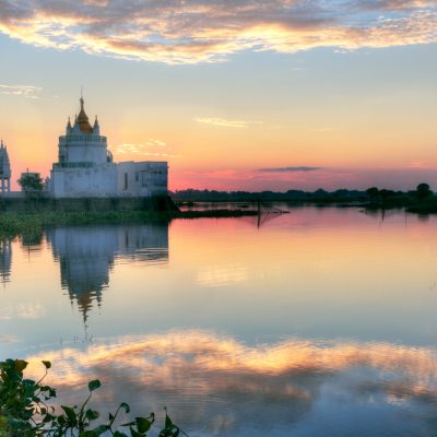 Buddhist temple at sunset reflecting in lake near U bein bridge at Amarapura, Mandalay, Myanmar